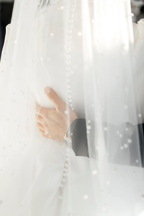 A bride is holding her veil in her hands