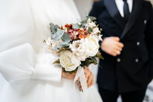 A bride and groom are holding a bouquet