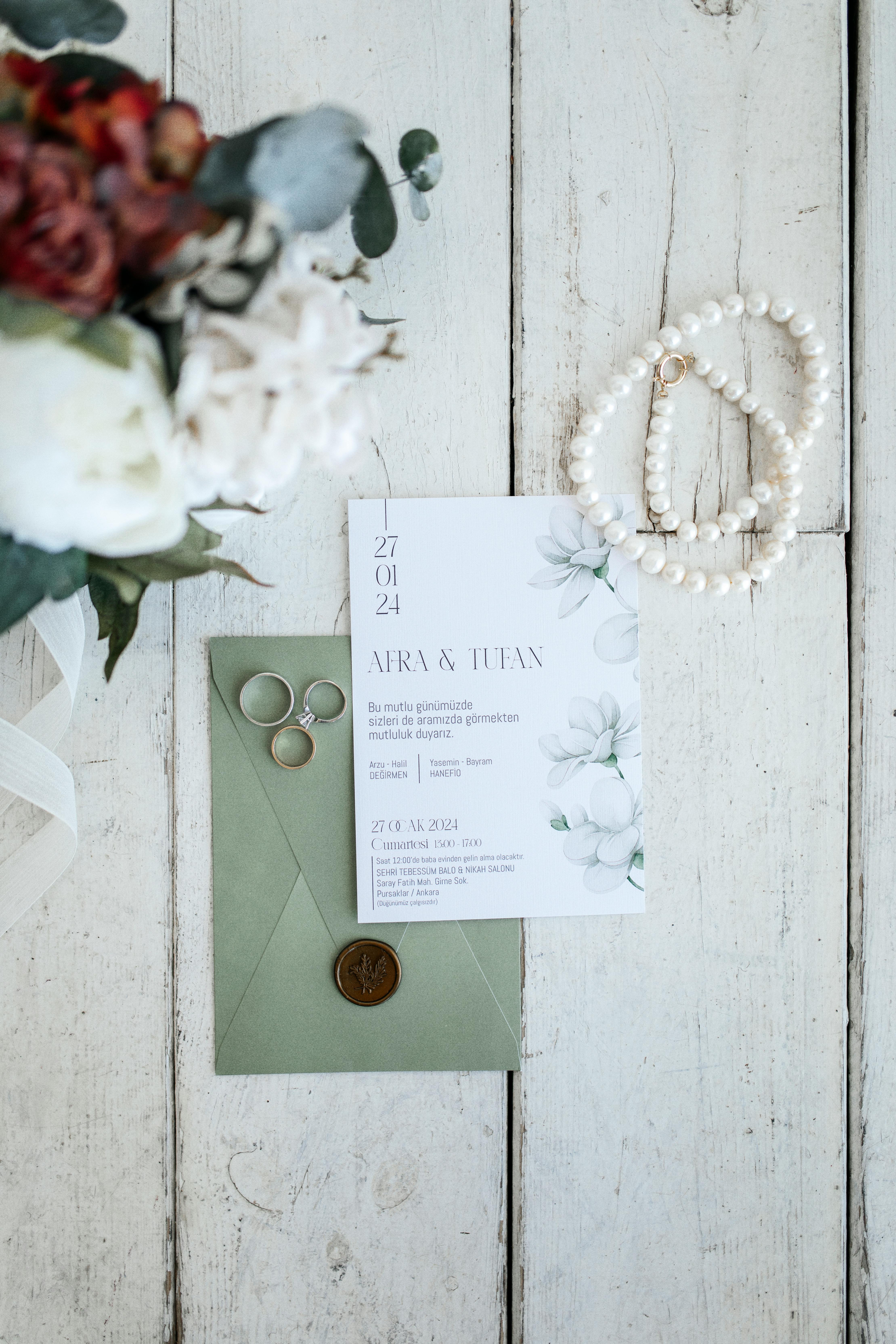 Beautiful display of wedding invitation, rings, and floral accents on a rustic wooden surface.