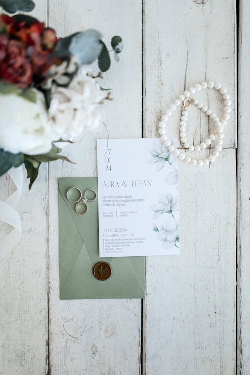 A wedding invitation and jewelry on a wooden table