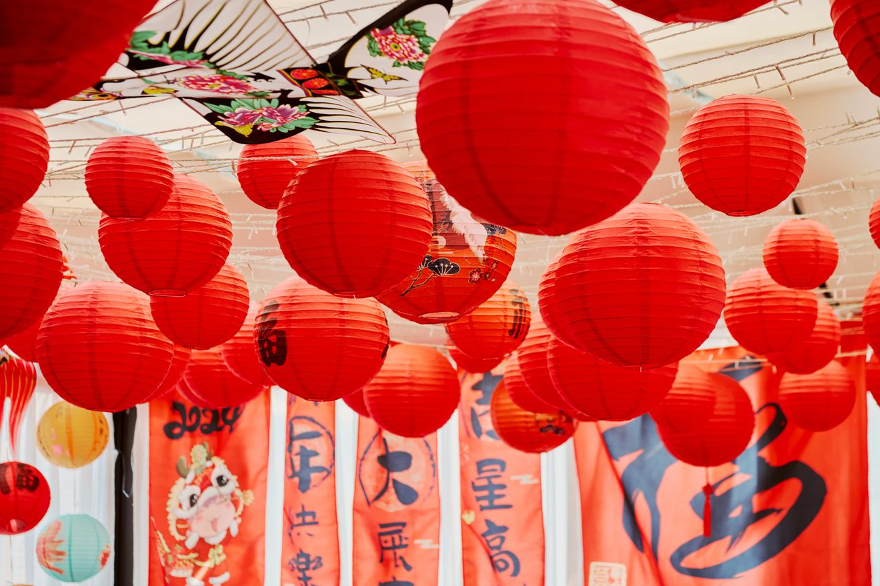 vibrant red chinese lanterns hanging indoors with decorative banners