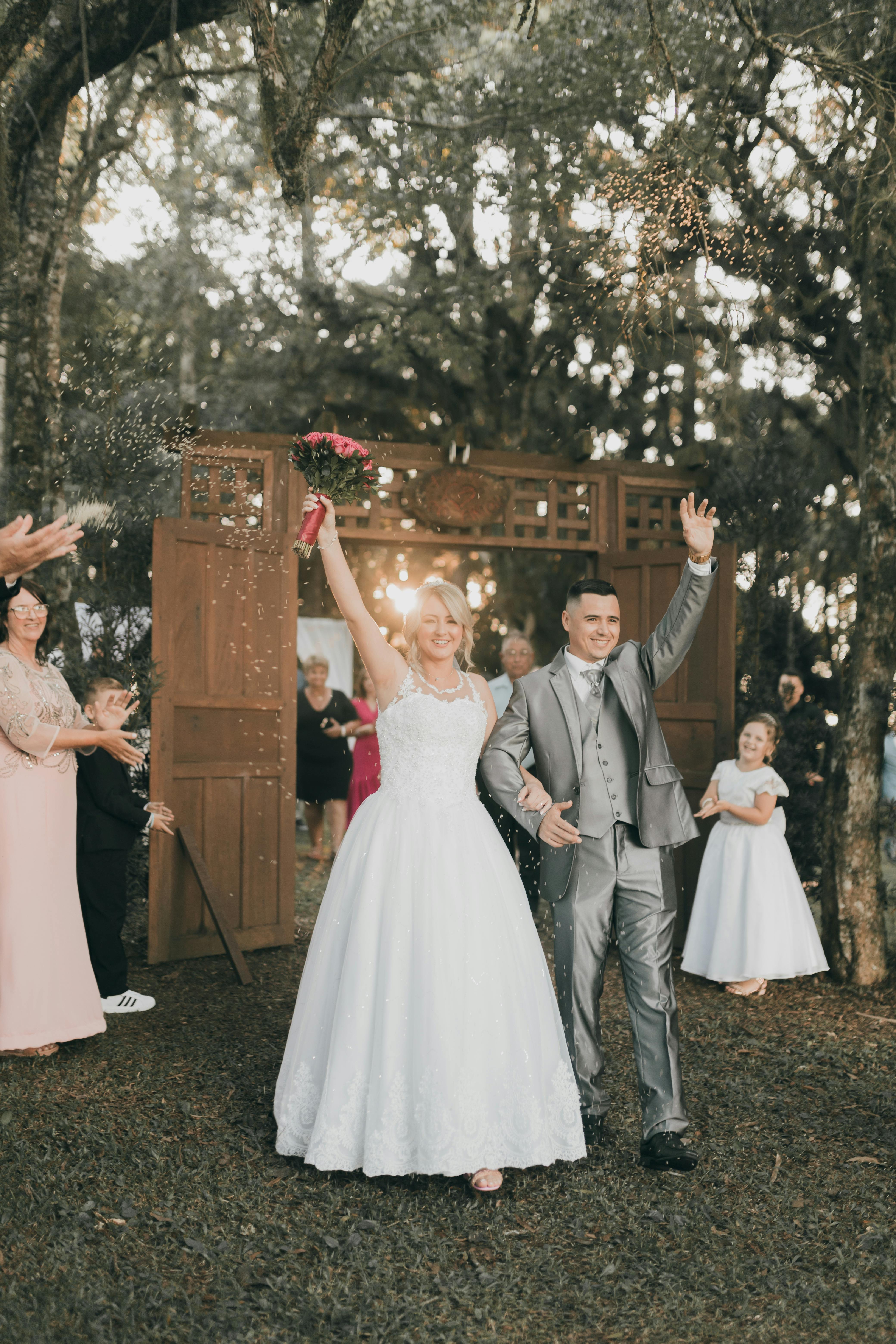 Celebratory wedding moment with a cheerful newlywed couple outdoors surrounded by guests.