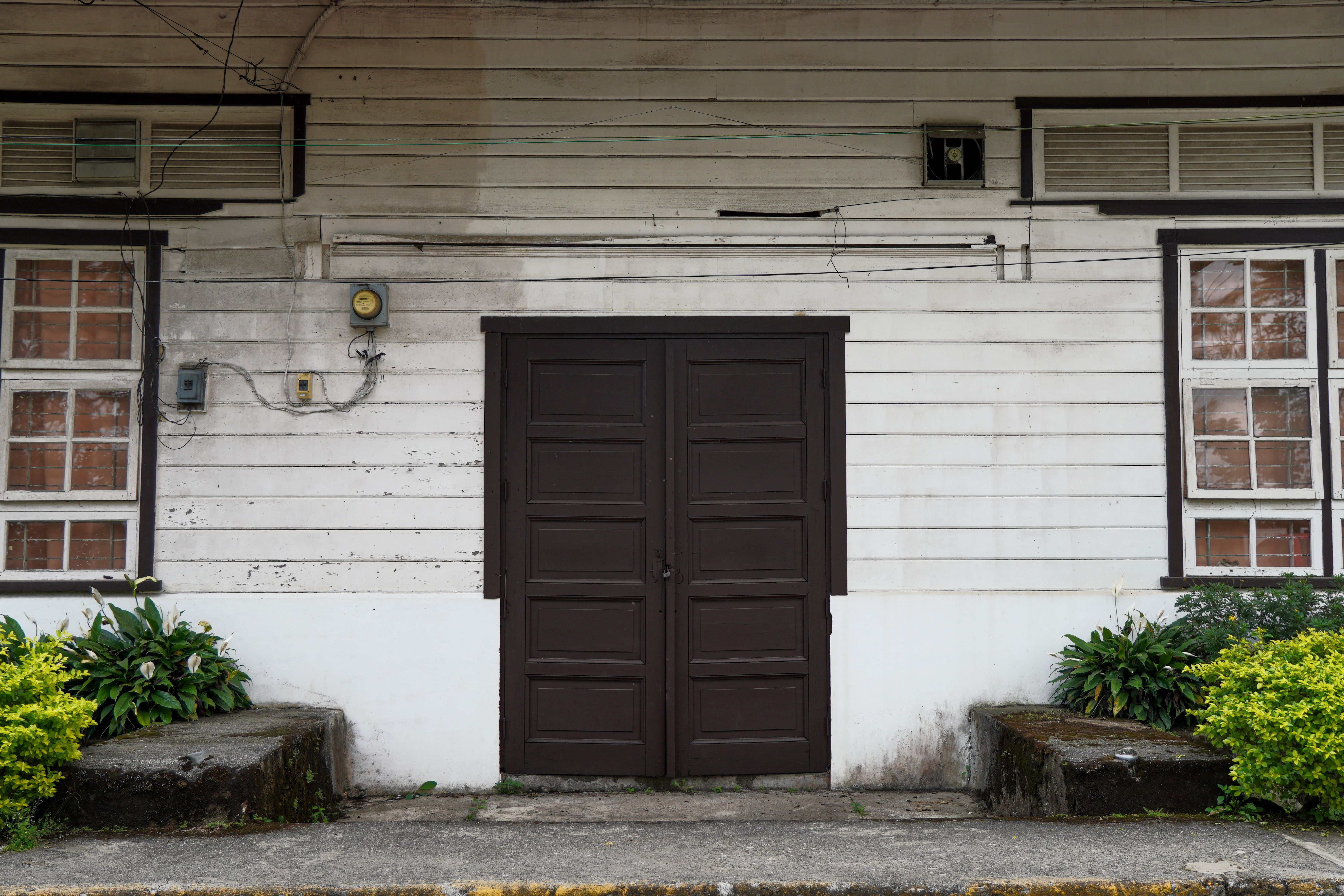 A rustic wooden door and windows on an aged building facade in La Trinidad, Philippines.
