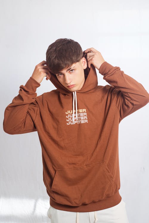 A man in a brown hoodie is posing for a photo