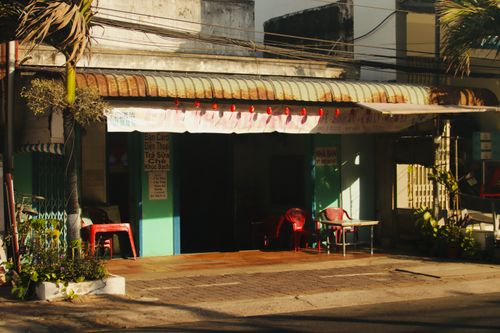 Free An inviting street view of a quaint urban cafe with outdoor seating and warm sunlight. Stock Photo