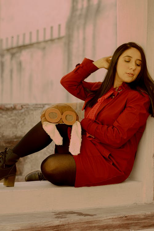 A woman sitting on a ledge with a stuffed animal