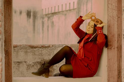 Free Woman in a red retro outfit posing playfully with an aviator cap outdoors. Stock Photo