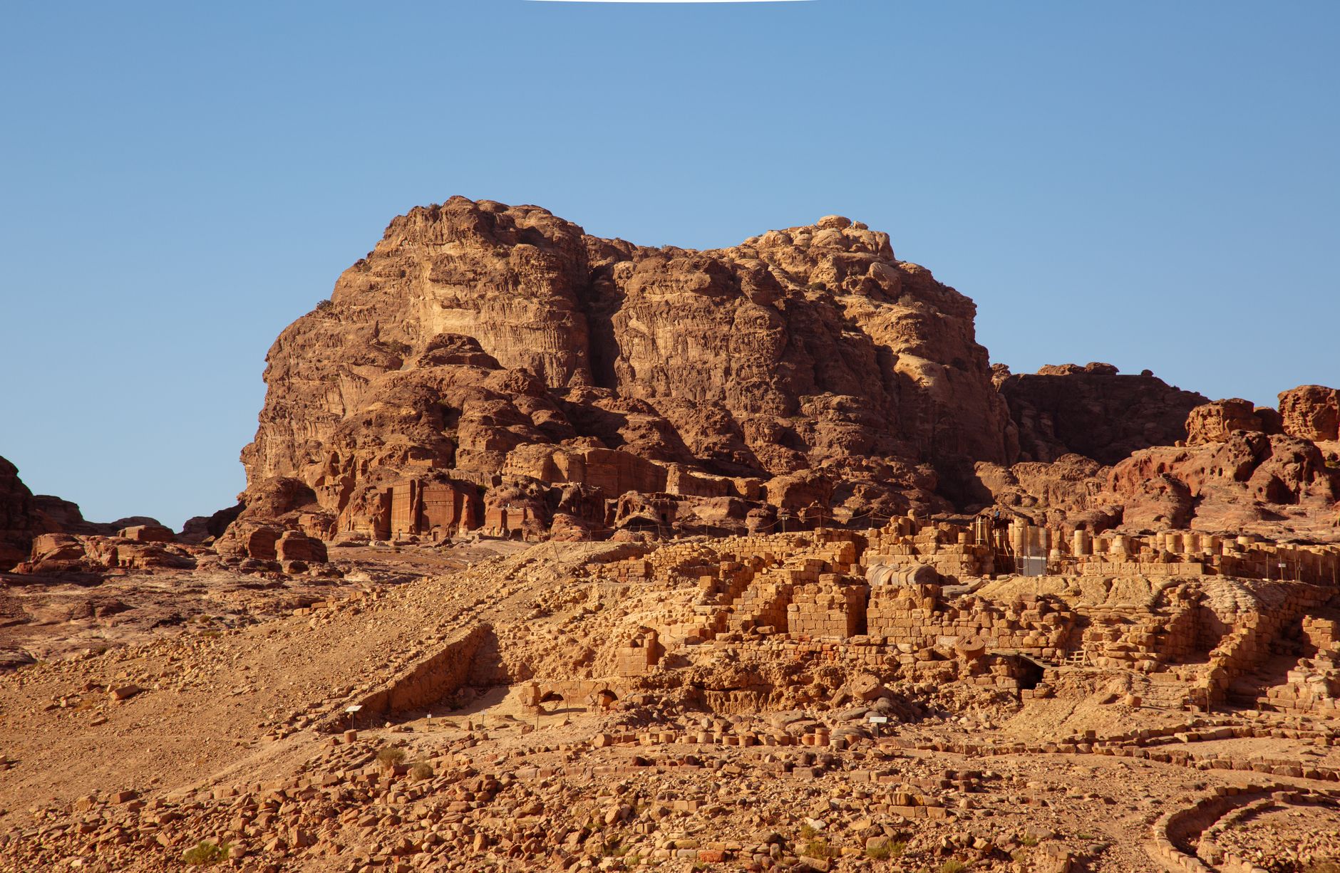 Explore the stunning ancient ruins under a clear blue sky in Petra, Jordan.