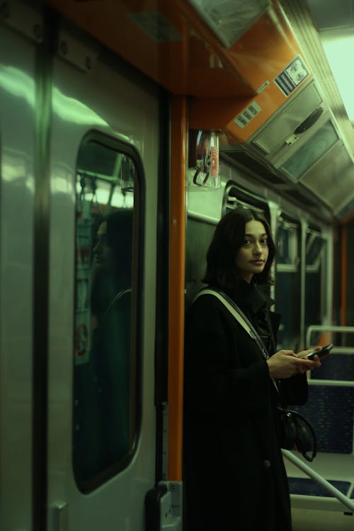 A woman standing on a subway train looking at her phone