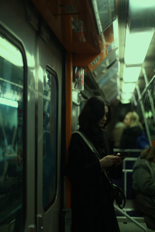 A woman is looking at her phone while riding a subway