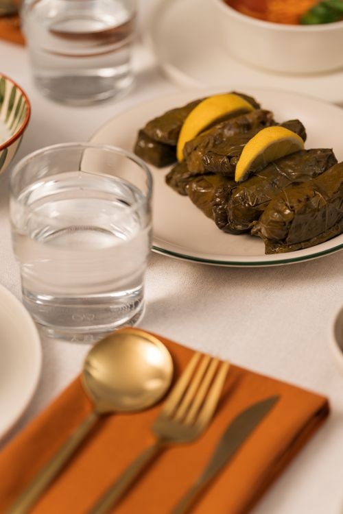 Free Close-up of a well-set dinner table with stuffed grape leaves and lemon slices. Stock Photo