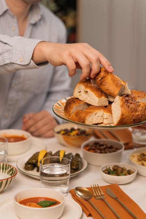 Free Hand reaching for freshly baked bread at a festive dinner table setting. Stock Photo
