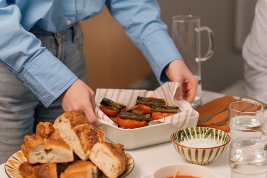A person setting a table with grilled vegetables and bread, perfect for a cozy dinner atmosphere.