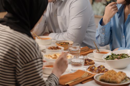 Free A relaxed meal setting with friends, enjoying diverse dishes and lively conversation. Stock Photo