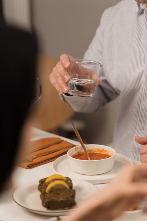Free A man enjoys a dinner with tomato soup and water, creating a cozy dining atmosphere. Stock Photo