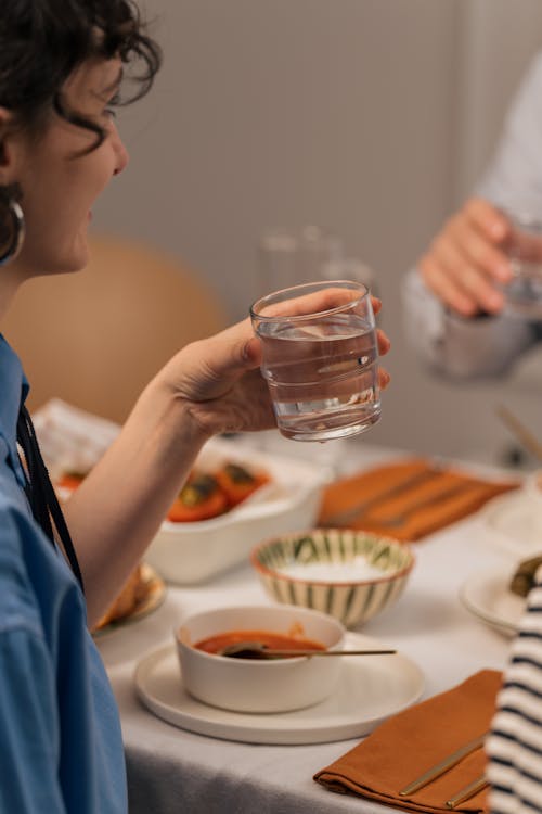 A woman drinking water at a dinner table