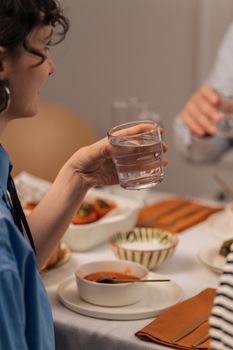 Adults enjoying a meal with glasses of water at an indoor dining table setting.