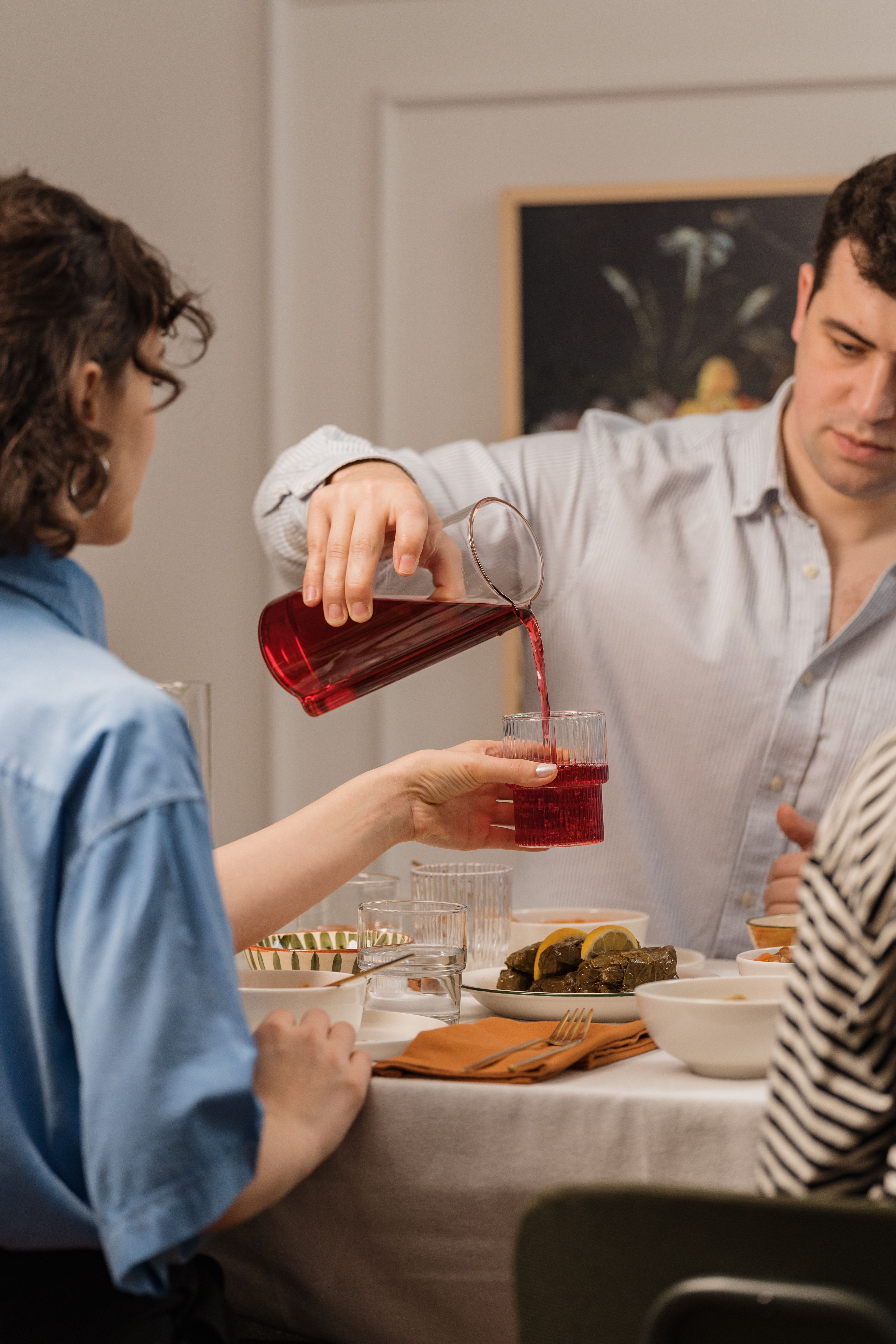 A group of adults enjoying a casual indoor dining setting with red juice being poured.