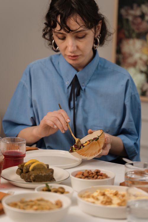 Free Woman eating a Mediterranean meal at a table with various dishes indoors. Stock Photo