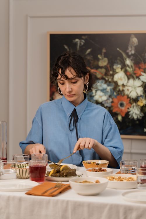Free A woman elegantly dining indoors with a variety of dishes, including a pickle plate. Stock Photo
