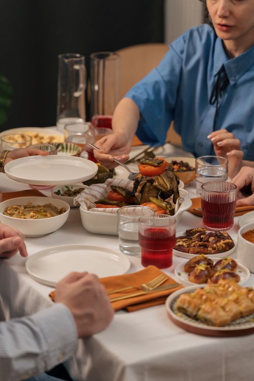 Free A family enjoying a meal together, sharing diverse dishes on a table set for a gathering. Stock Photo