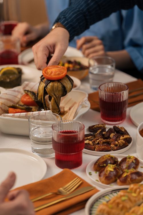 Free Close-up of a group enjoying a Mediterranean meal with various dishes and red drinks. Stock Photo