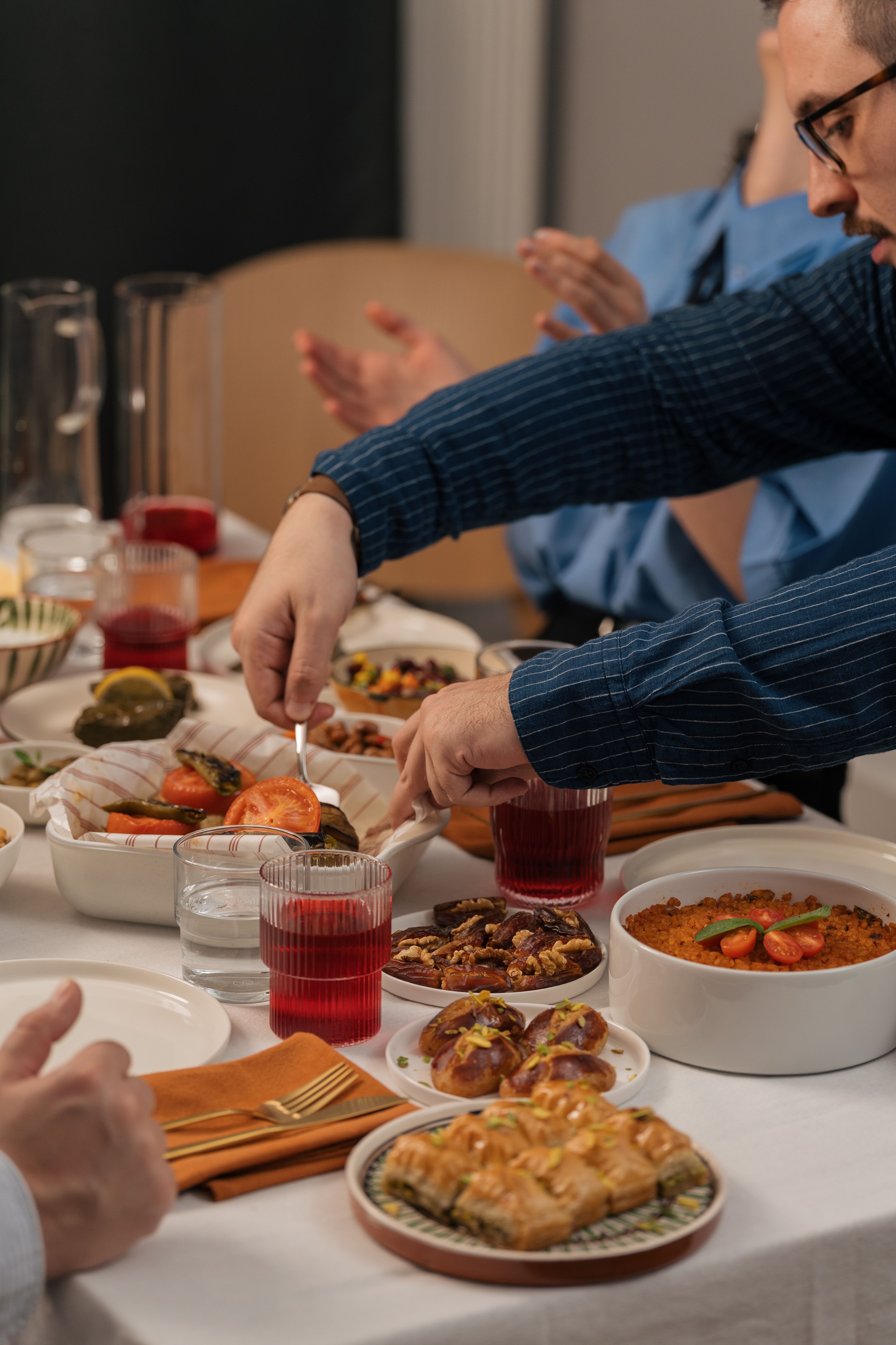 Cozy indoor family dinner with a variety of dishes served on a table, featuring hands reaching for food.