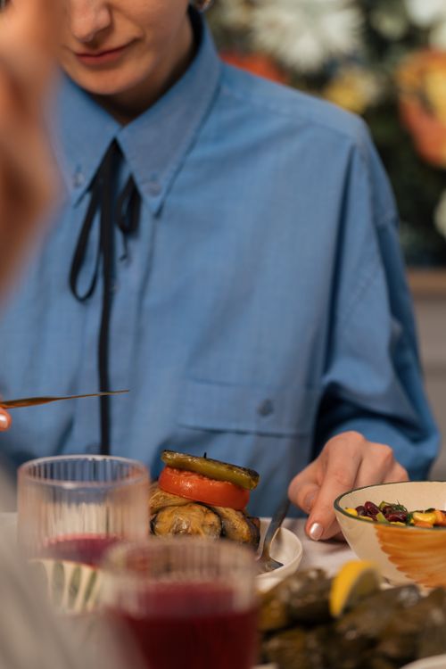 Free A woman in a blue shirt enjoying a Mediterranean meal with selective focus on food. Stock Photo