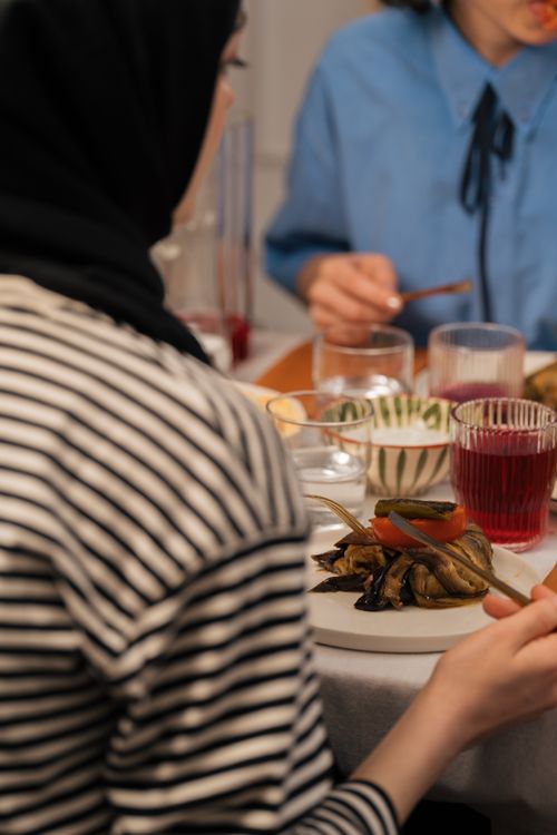Free Adults enjoying a casual indoor meal with drinks and food on a table. Stock Photo