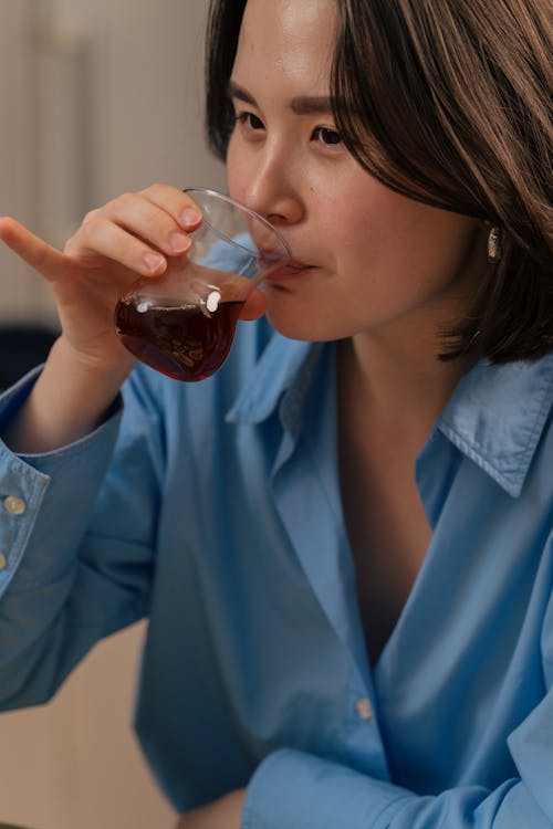 A woman drinking from a glass of red wine