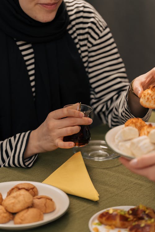 A woman in a hijab is eating food with a friend