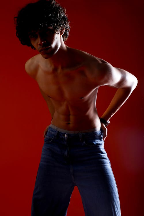 A shirtless man in jeans poses for a photo