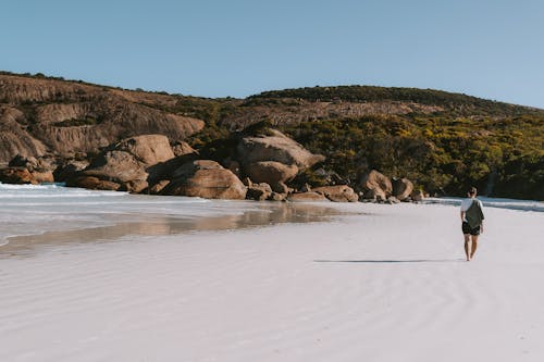 A person walking on a white sand beach