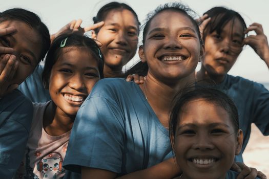 A group of happy young friends smiling and posing together outdoors in warm natural light.
