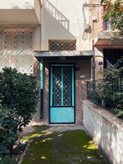 Free A sunlit urban doorway surrounded by greenery, showcasing vintage style and architectural charm. Stock Photo