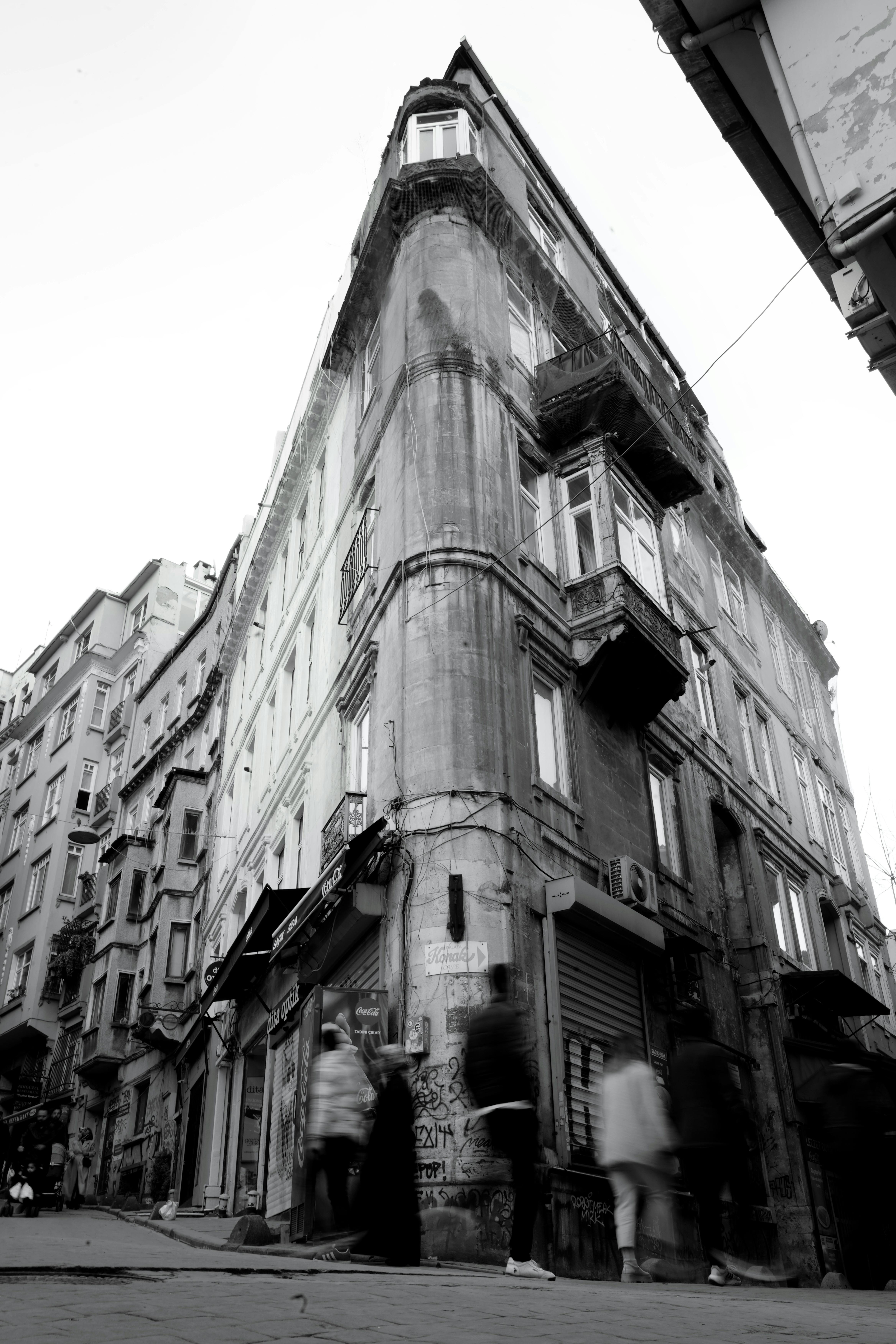 Free Black and white photo of a classic city building with blurred pedestrians, evoking urban life. Stock Photo