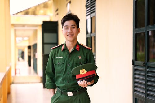 A young man in uniform holding a hat
