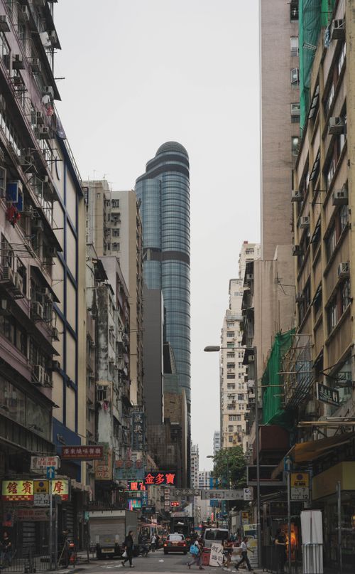 Free Bustling city street in Hong Kong with towering skyscraper and vibrant urban life. Stock Photo