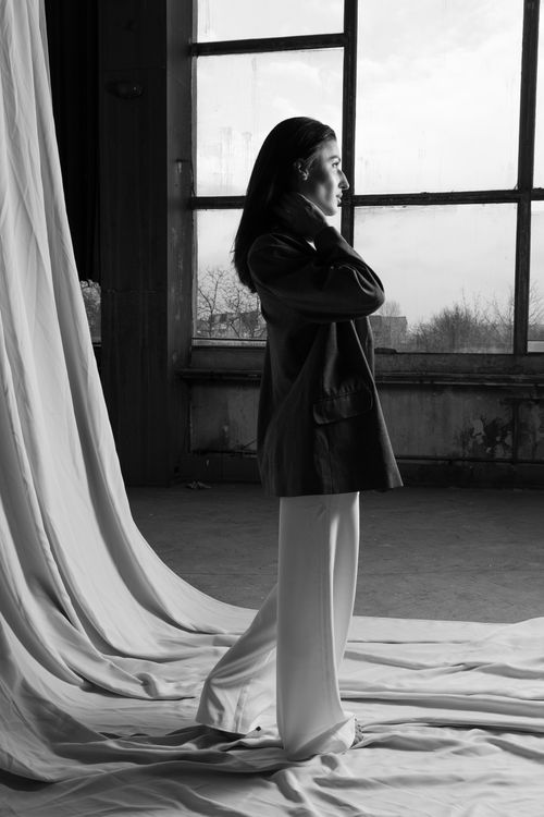 Free Elegant woman in a blazer poses artistically in a black and white studio setting. Stock Photo