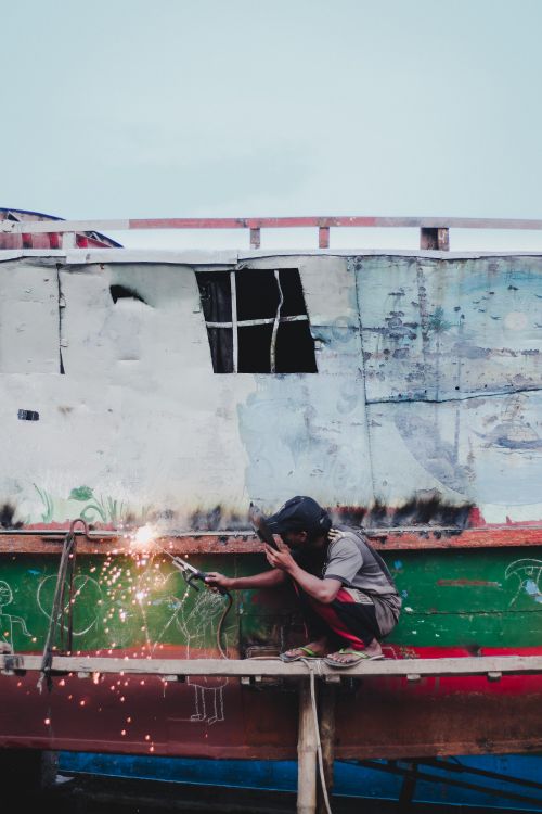 Free Man welding on a boat in Chilmari, Bangladesh, displaying sparks and craftsmanship. Stock Photo