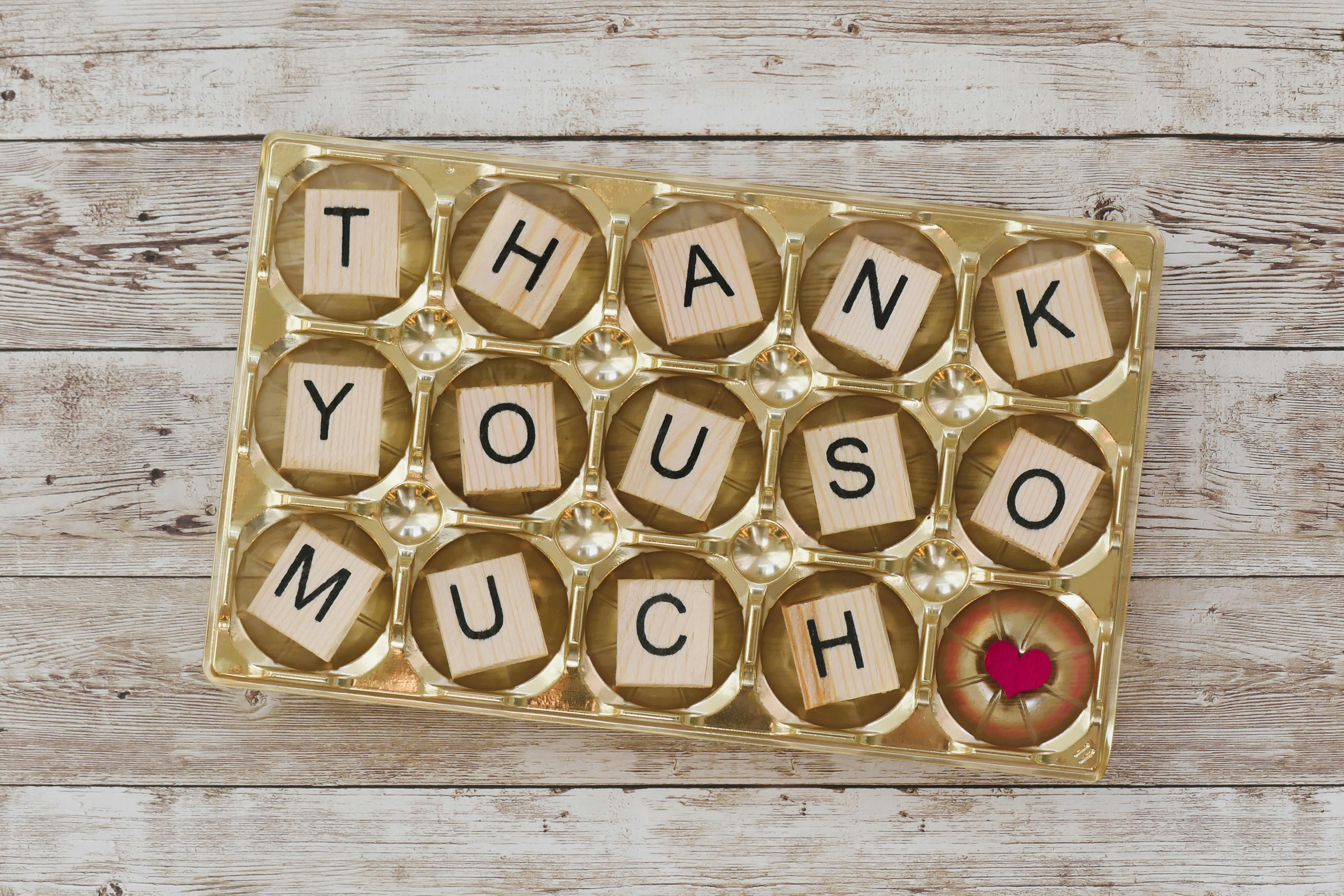 Creative thank you message with wooden block letters in a golden tray. Perfect for appreciation cards.