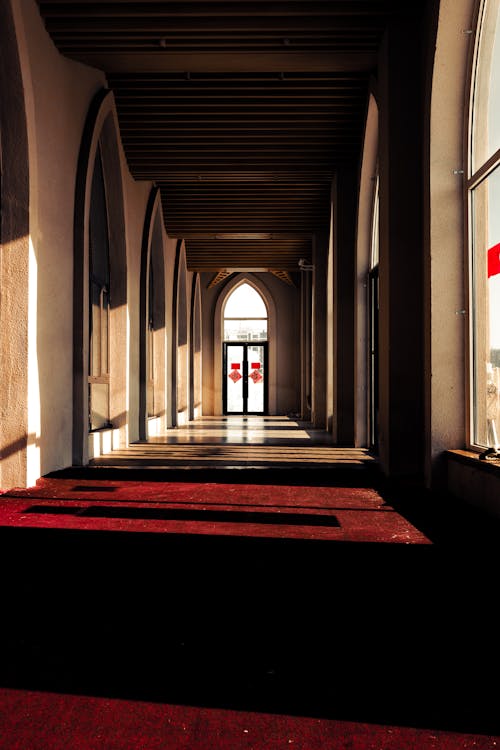 A long hallway with red carpet and a window