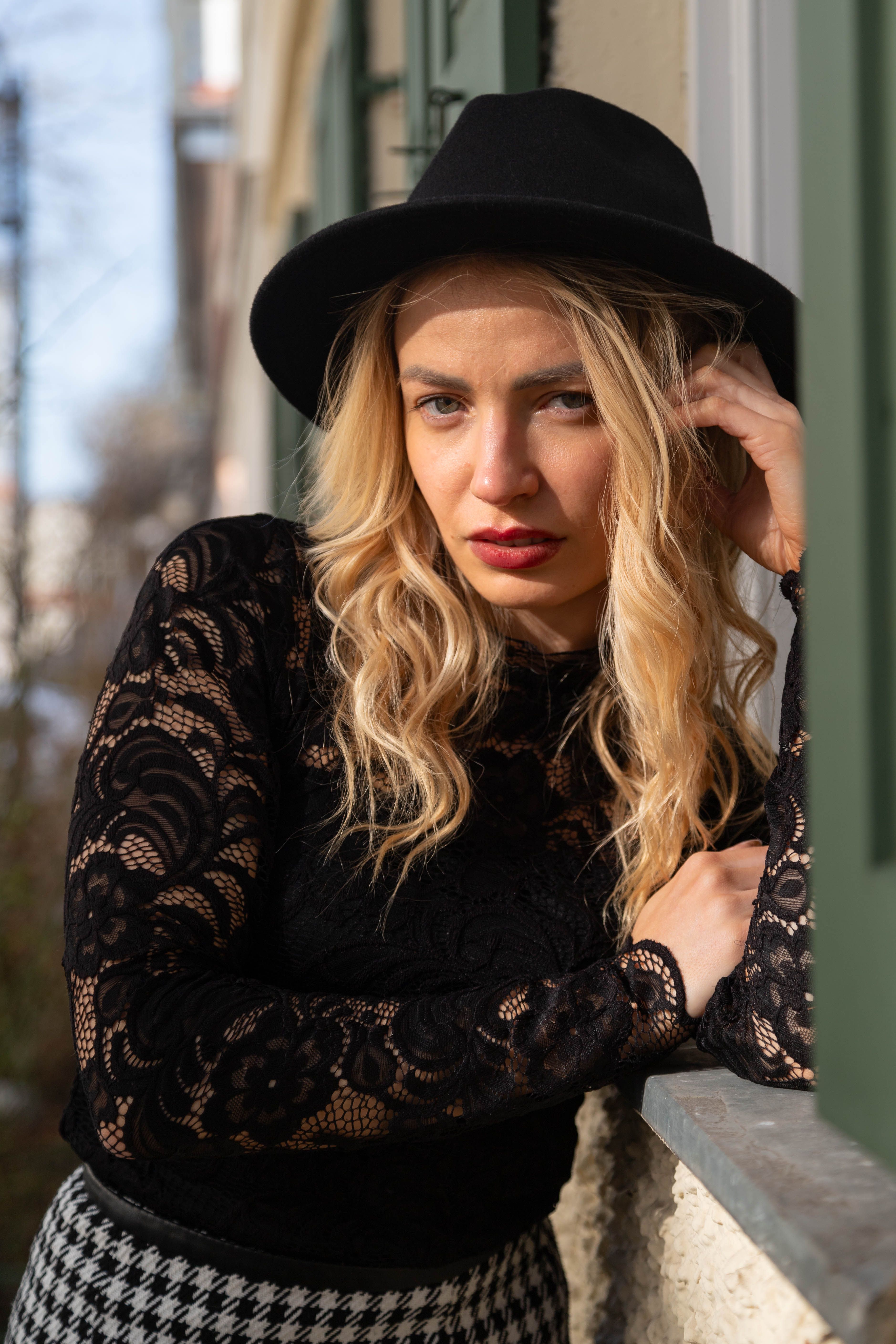 Blonde woman in a black lace blouse poses stylishly outside in Munich, Germany.