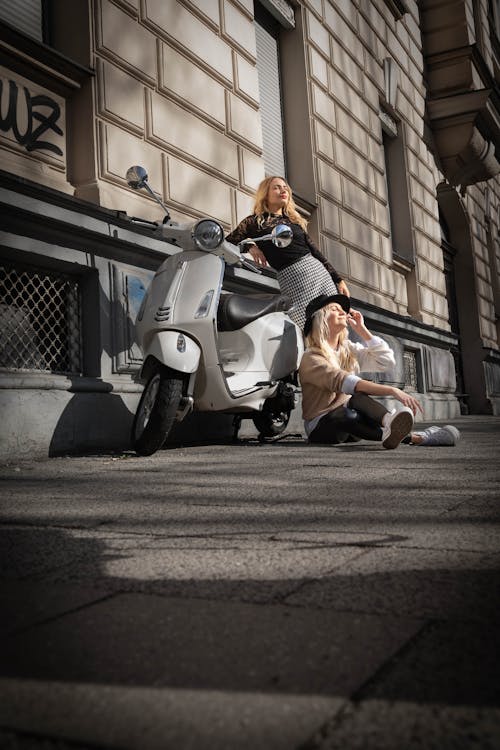 Women Posing next to a Scooter on a Pavement