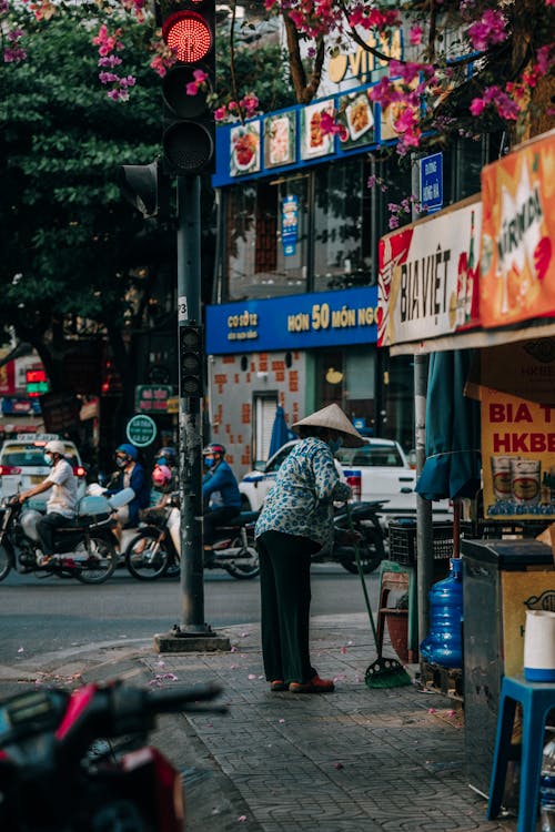 Free A woman is walking down the street with a broom Stock Photo