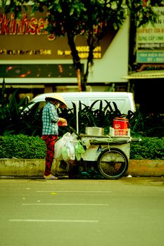 A street vendor with a food cart on an urban street in summer, showcasing daily city life.