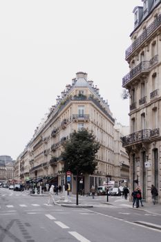Urban street scene in Paris featuring classic architecture, pedestrians, and vehicles.