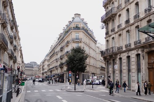 Free Bustling Paris street lined with classic historic buildings and pedestrians. Stock Photo