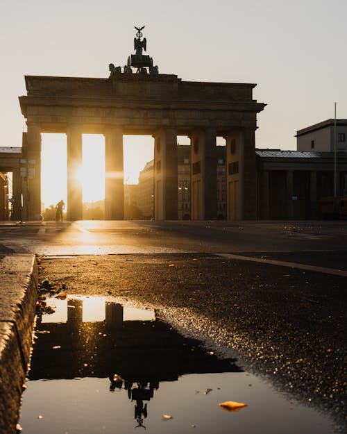 The sun is setting over the brandenburg gate in berlin