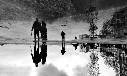 A black and white photo of people walking on the beach